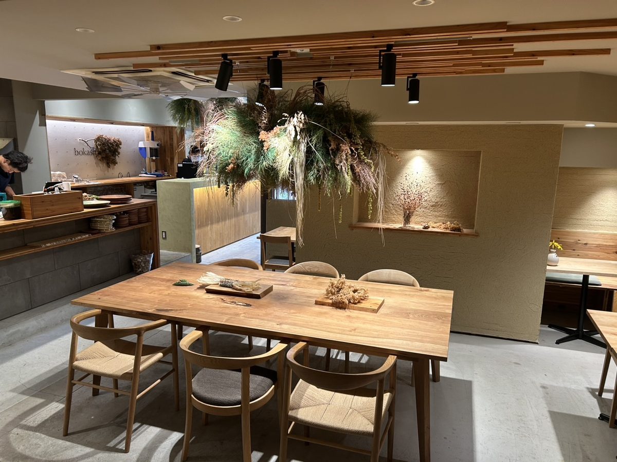 カフェ「bokashi」の店内。木のテーブルと椅子が並んでいる